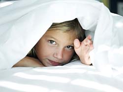 Ребенок выглядывает из-под одеяла